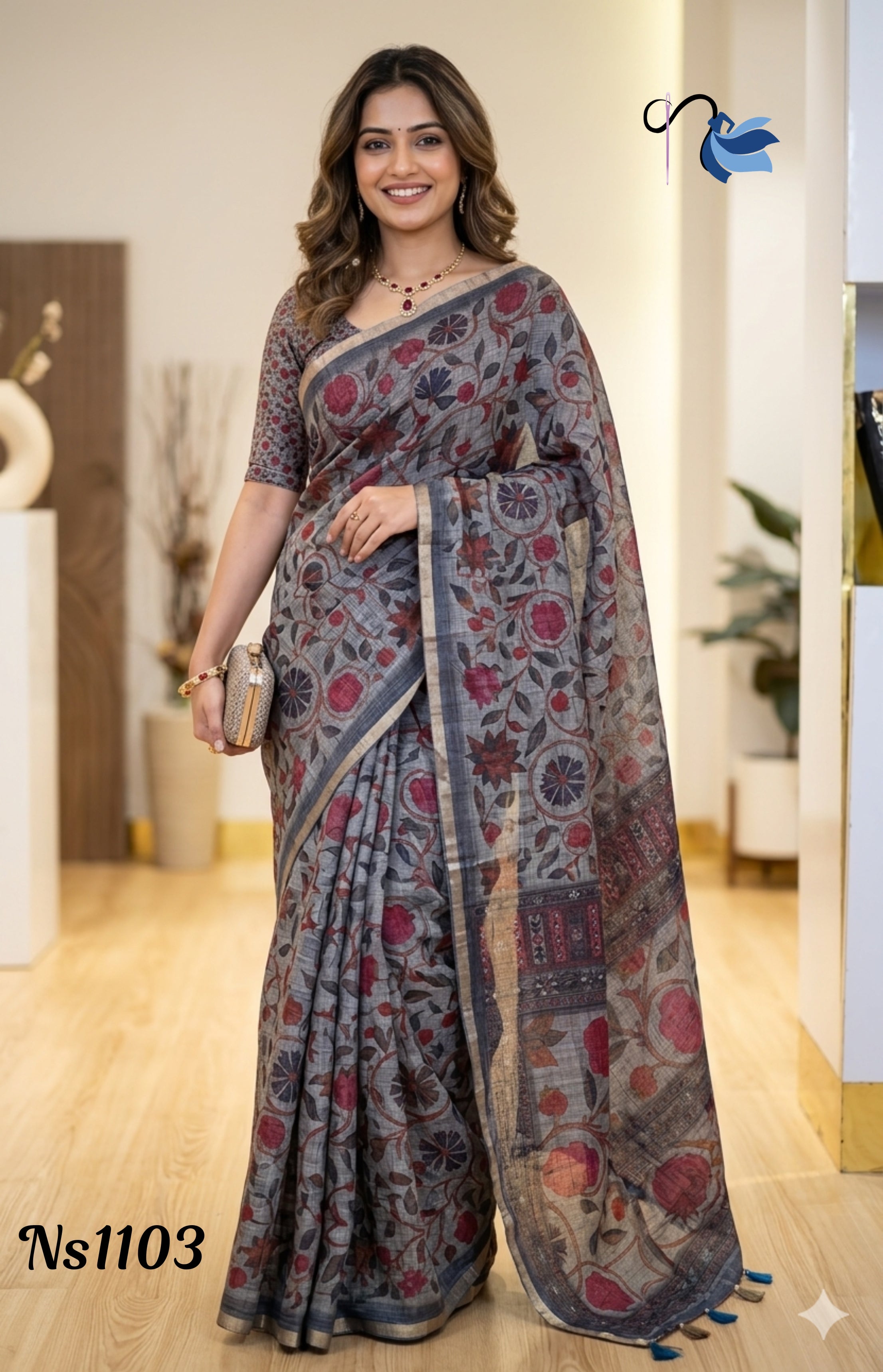 Woman wearing a grey linen saree with maroon floral Kalamkari prints and a gold zari border, holding a gold clutch.